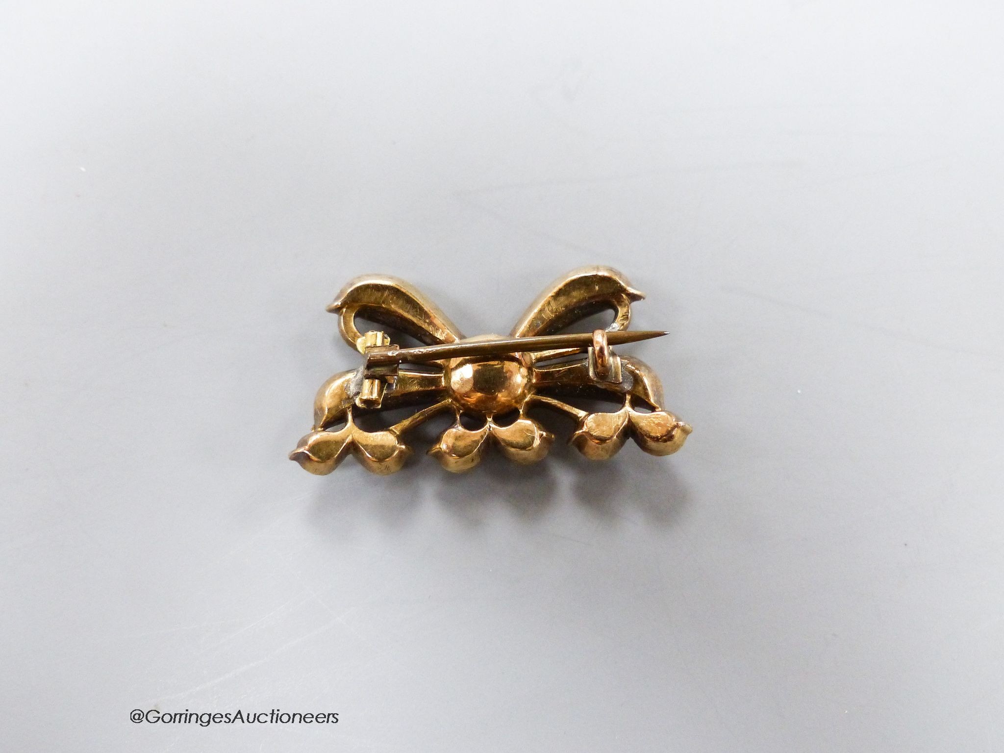 An early 20th century yellow metal and citrine cluster set ribbon bow brooch, with closed back setting, 30mm, gross 6.2 grams.